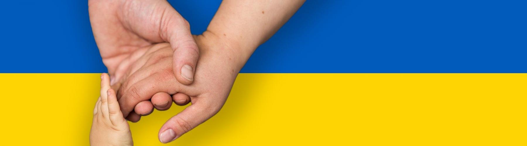 mains d'homme, femme et enfant qui se tiennent devant le drapeau ukrainien