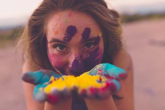 Femme avec pigments de couleur sur les mains et le visage