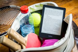 Sac de sport ouvert avec raquettes, balles, bouteille d'eau et liseuse