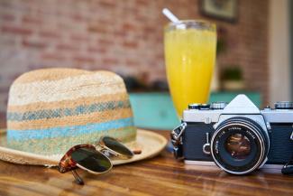 Chapeau de paille, lunettes de soleil, cocktail fruitée et appareil photo
