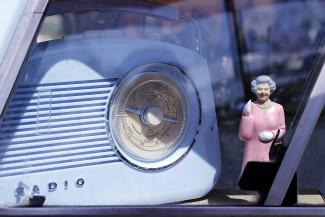 Figurine représentant la Reine d'Angleterre à côté d'un vieux post de radio